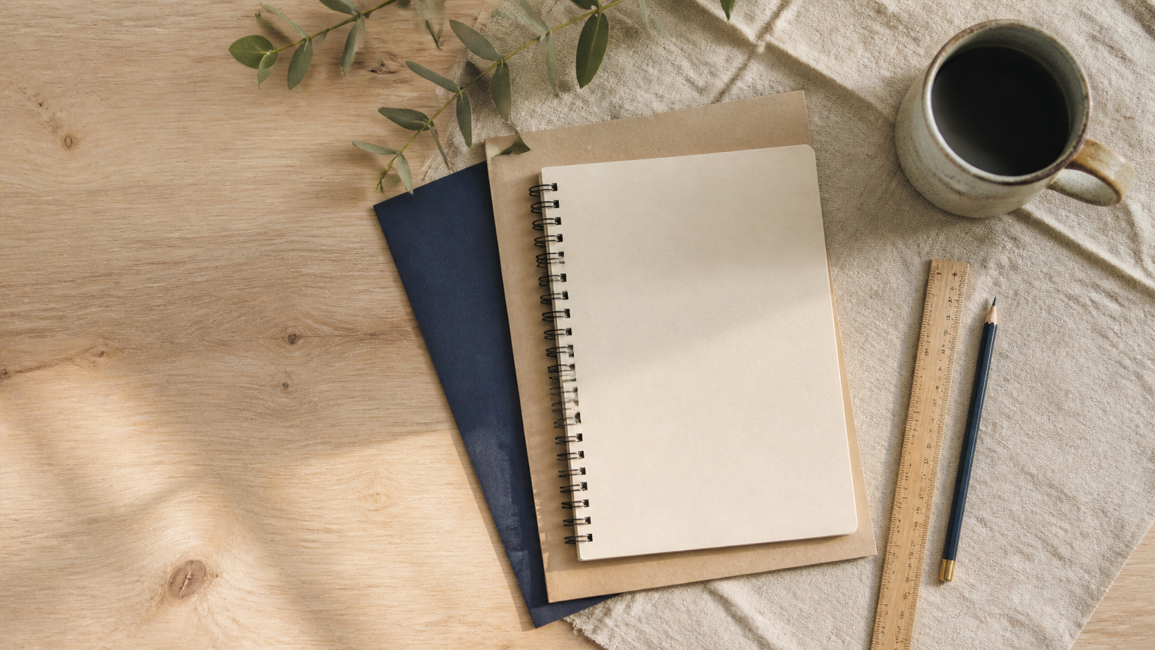 A plain notebook, ruler and pencil on linen and recycled paper with visible fibres and wood grain.